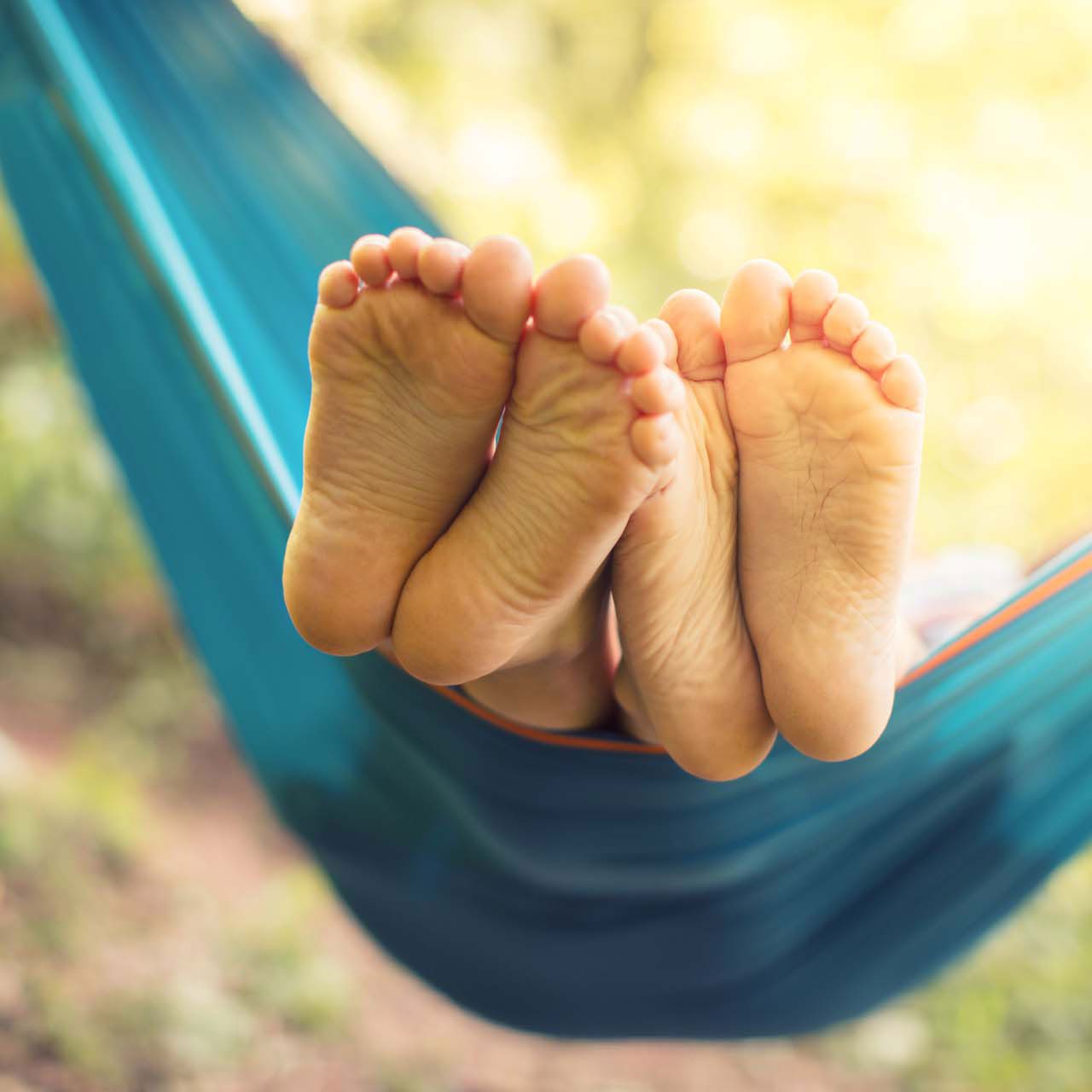 Two pairs of bare feet resting in a hammock, symbolising the relaxed moments in the UK adoption process