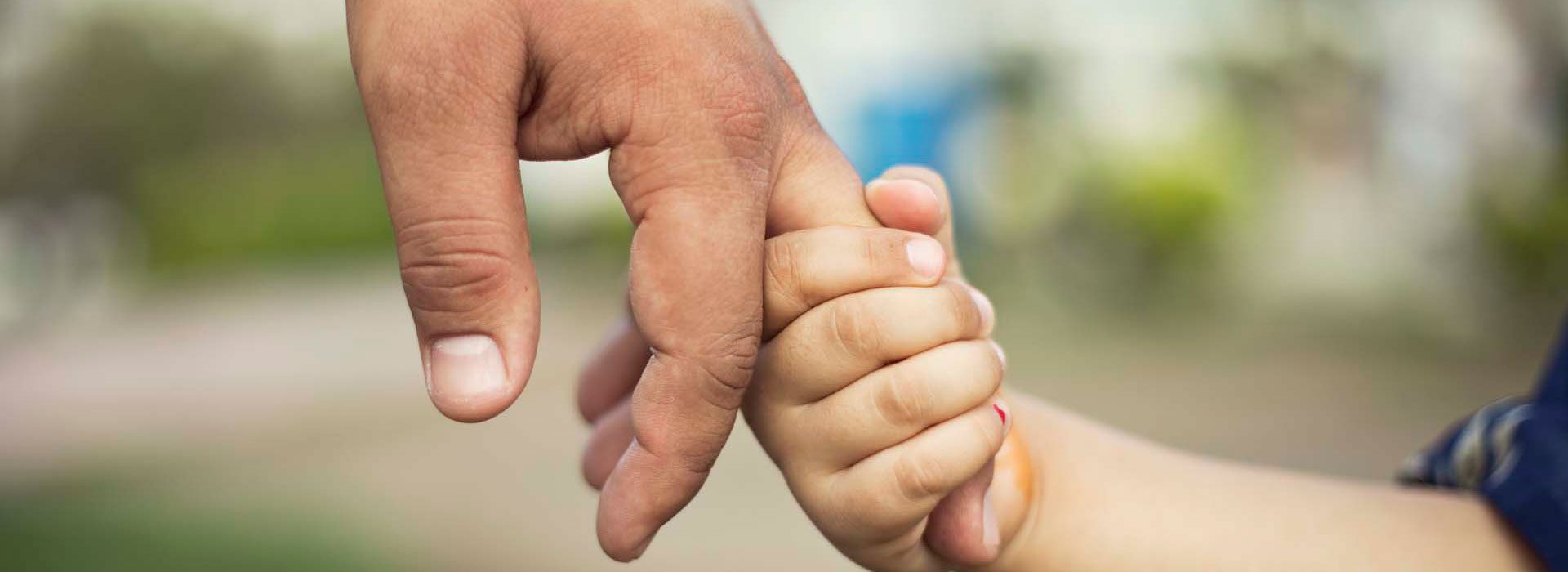 An adult's hand holding a child's hand, a sign of trust and guidance in the adoption journey in the UK