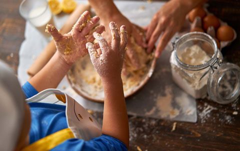 Little hands covered in flour during a baking session with a family member, a common bonding activity in adoptive homes