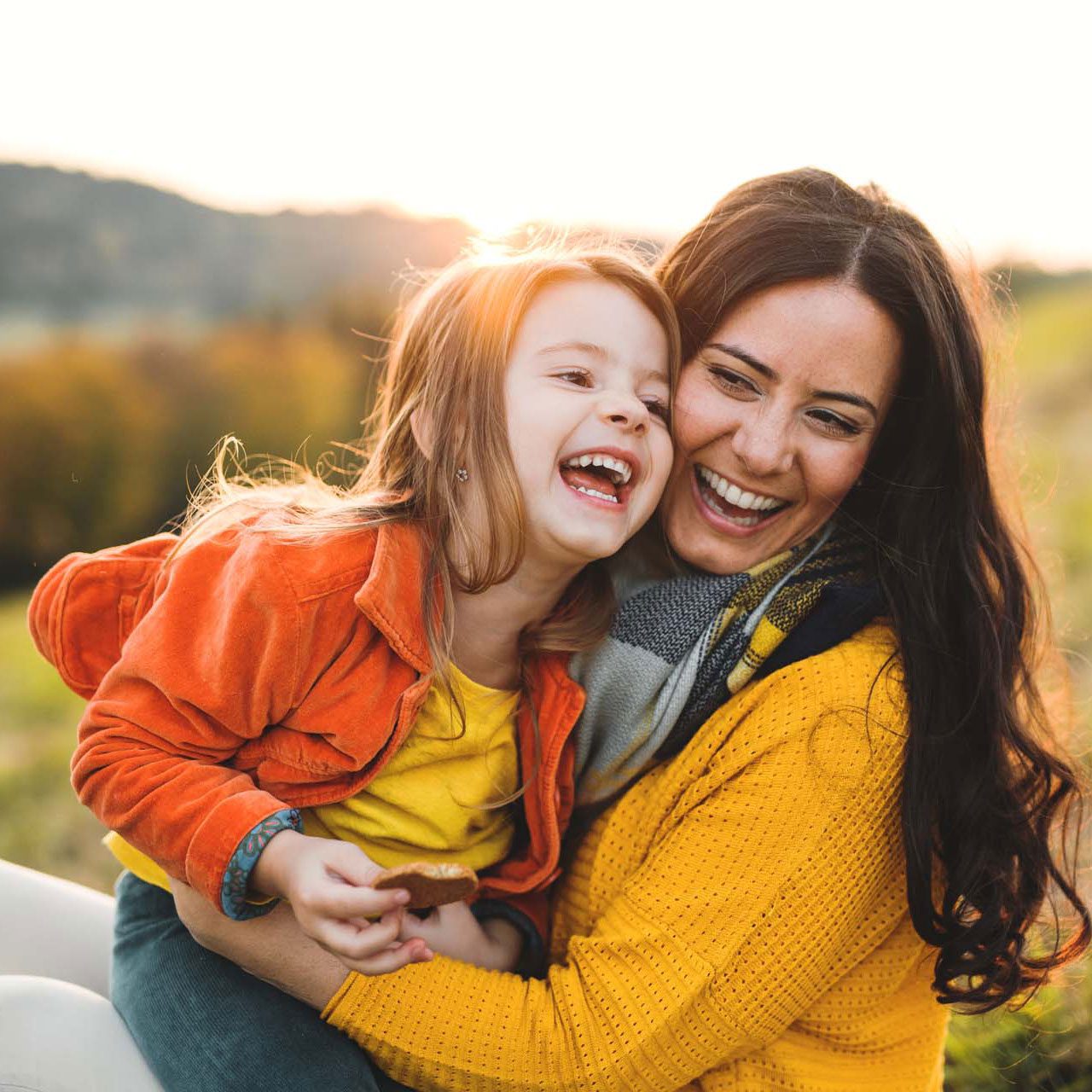 A guardian and child share a hearty laugh in the golden hour sunlight, a moment of genuine connection in a UK adoptive home