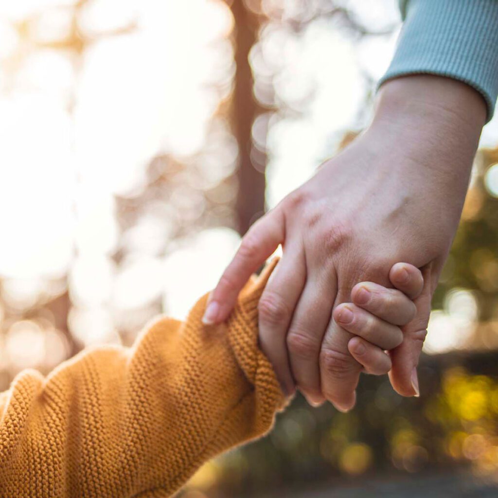 Adult and child holding hands in a warm embrace, a common reassuring gesture in the adoption process UK